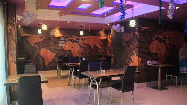 Un restaurant au décor rustique, avec des tables et des chaises en bois, et une fresque murale.