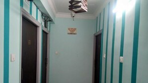 Un couloir aux murs rayés de turquoise, avec deux portes, dont l’une porte un panneau interdisant l’introduction de nourriture provenant de l’extérieur.