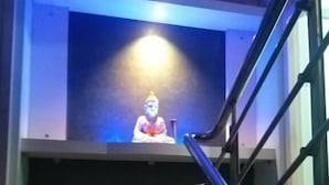 Un escalier menant à une pièce où se trouve une statue de Bouddha, éclairée par un projecteur.