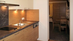 A compact kitchen with a sink, stove, and wooden cabinets. - Beautiful apartment for 2 people with WIFI, TV and balcony (Fendels)