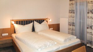 A double bed with a wooden headboard, two bedside lamps, and a radiator. - Beautiful apartment for 2 people with WIFI, TV and balcony (Fendels)