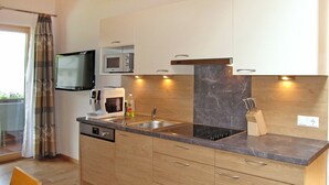 Een moderne keuken met houten kastjes, een ingebouwde magnetron, een spoelbak en een messenblok.