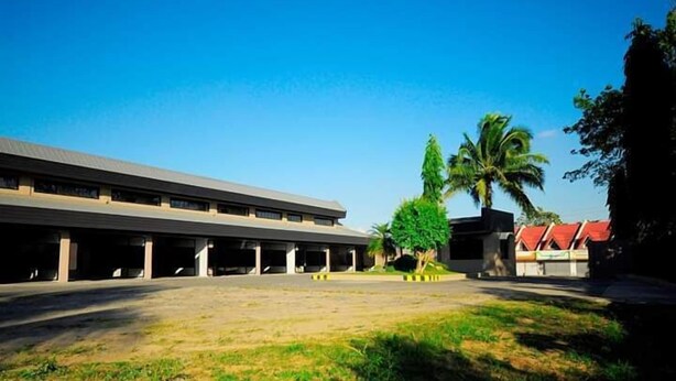 Un edificio con techo plano, múltiples columnas y un área de estacionamiento techada.