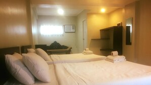 Habitación de hotel con dos camas, una mesita de noche con lámpara, un espejo y una ventana con cortinas.