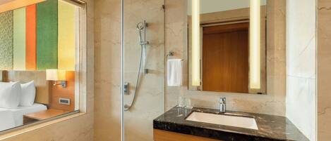 A modern bathroom with a glass-enclosed shower, a marble sink, and a large mirror.