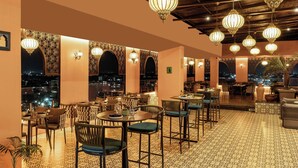 An indoor dining area with patterned flooring, tables with chairs, and decorative lighting. - The Fern Kolhapur, Series by Marriott (Kolhapur)