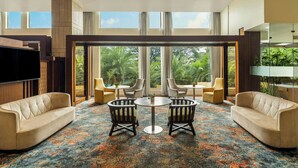 A spacious room with a large window, a sofa, two armchairs, a small table, and a flat-screen TV. - The Fern Kolhapur, Series by Marriott (Kolhapur)