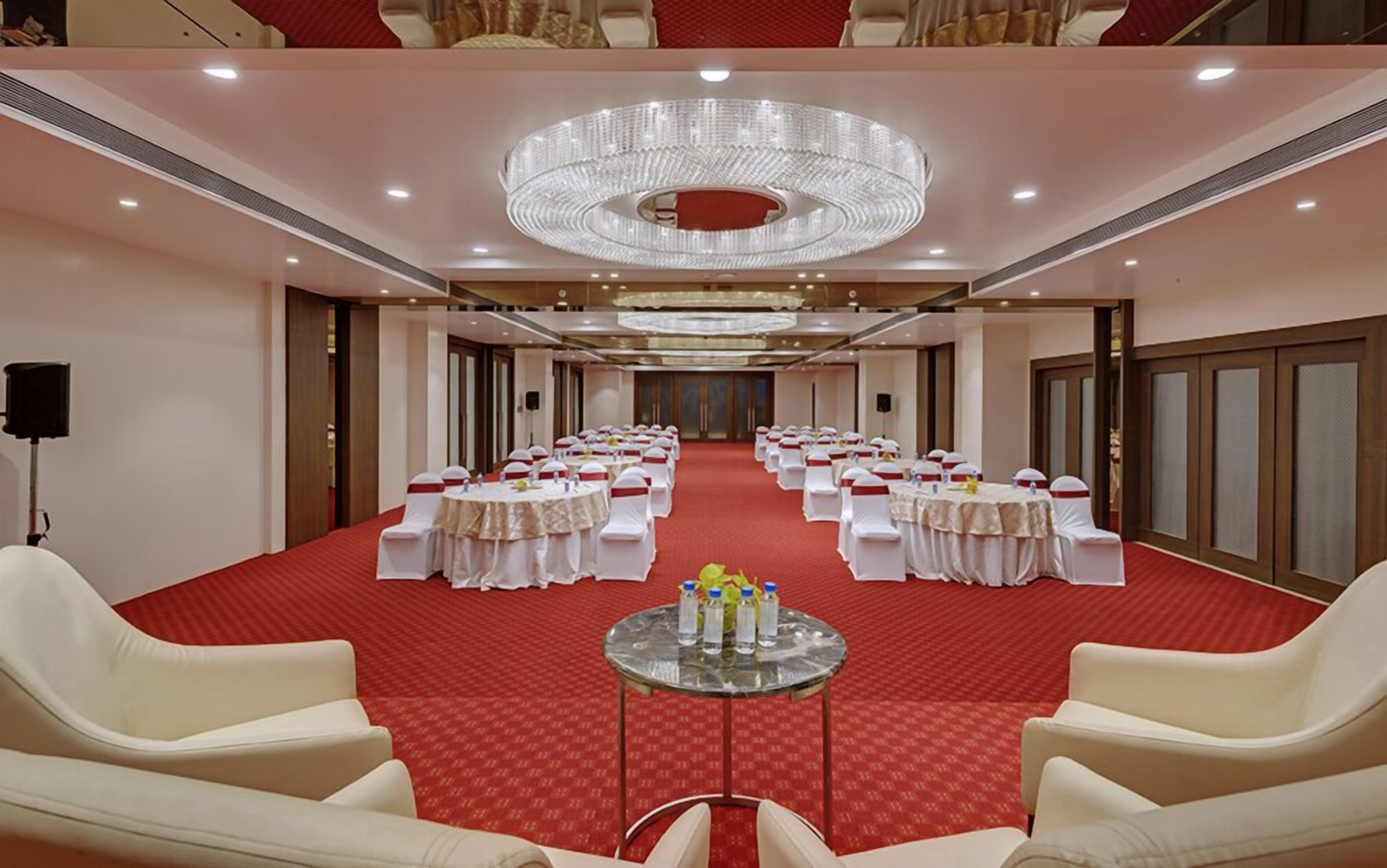 A conference room with round tables, white chairs, and a red carpet.