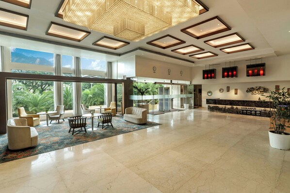 A spacious lobby with a high ceiling, large windows, and a seating area with modern furniture.