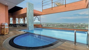 A rooftop infinity pool with a clear view of the cityscape, surrounded by lounge chairs and a wooden deck. - The Fern Kolhapur, Series by Marriott (Kolhapur)