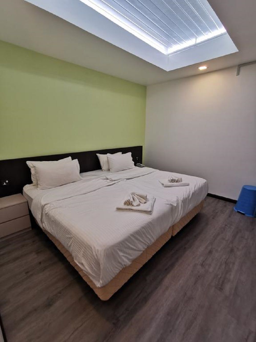 Een hotelkamer met dakraam, een bed met witte lakens en een houten vloer.