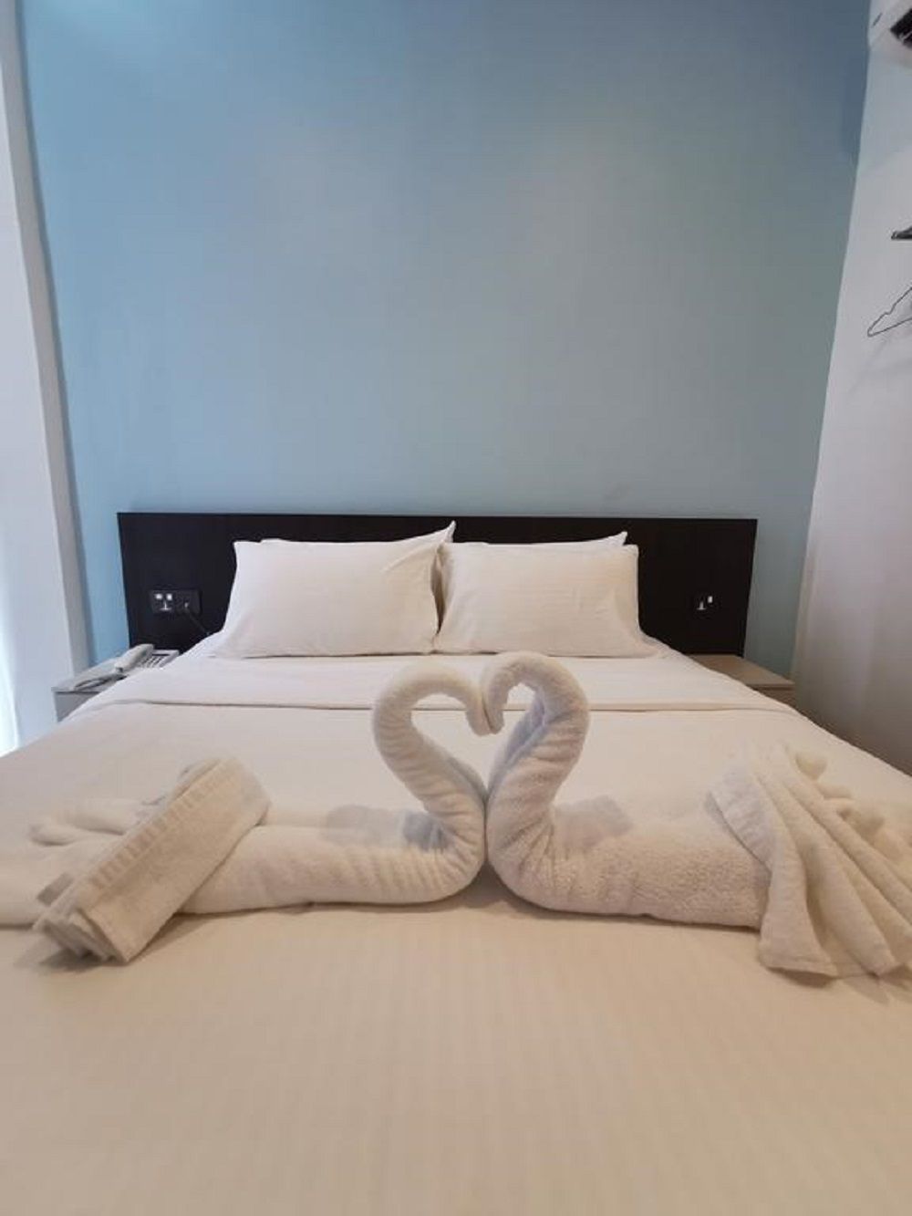 A hotel room with a bed, pillows, and towels arranged in a heart shape.