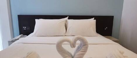 A hotel room with a bed, pillows, and towels arranged in a heart shape.