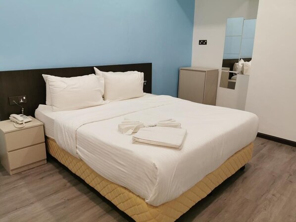 A neatly made bed with white linens and pillows, a bedside phone, and a folded towel on the nightstand. - TT Dorf Hotel Taiping (Taiping)