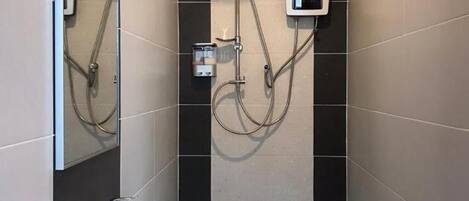 A modern bathroom with a white sink, a handheld showerhead, and a wall-mounted shower unit.
