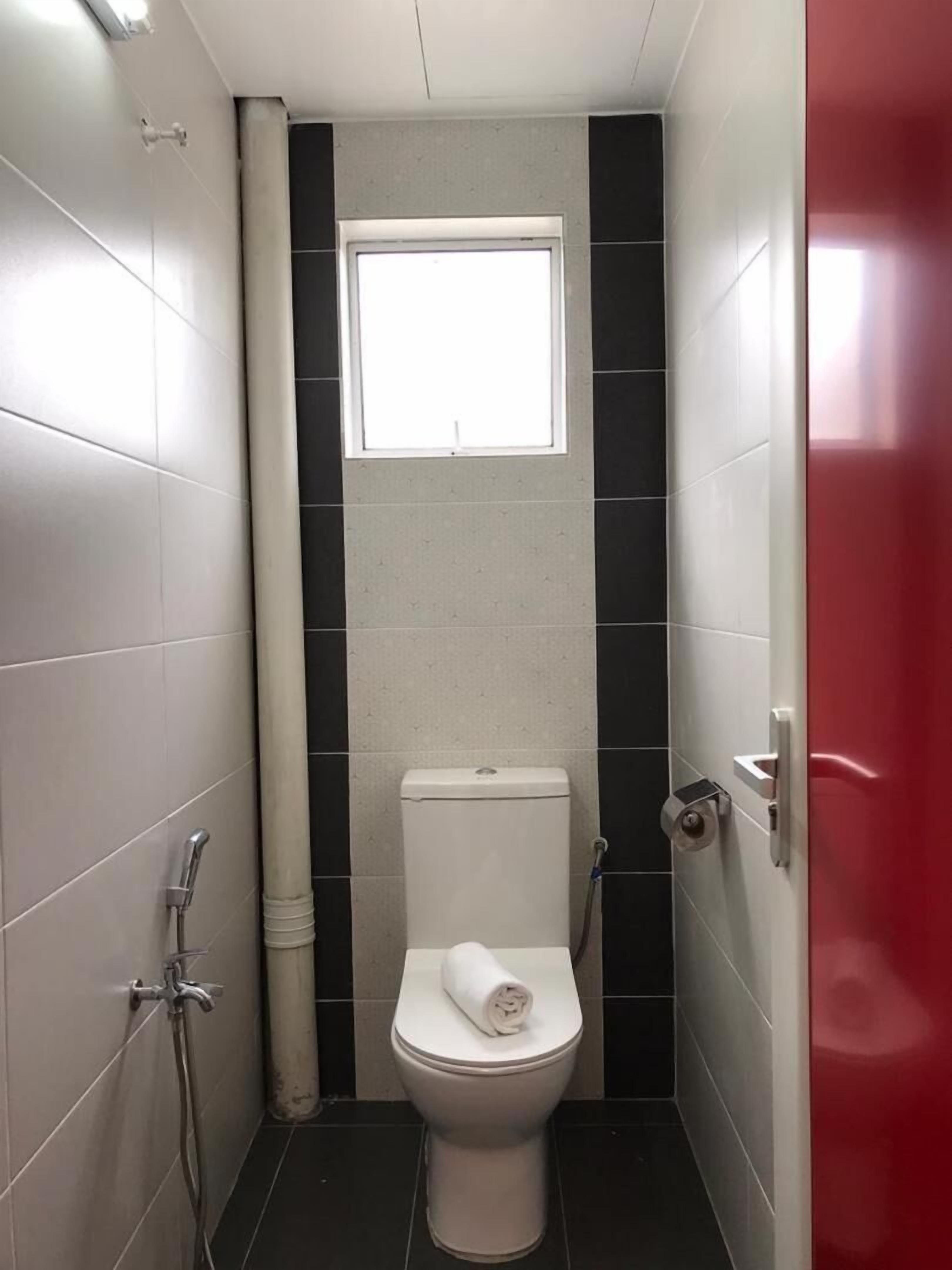 Un baño pequeño y moderno con inodoro, ducha y ventana.