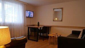 A cozy living room with a sofa, a small table, and a TV mounted on the wall. - Lovely apartment for 5 guests with WIFI and TV (Unter Eiger)