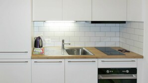 A modern kitchen with white cabinets, a stainless steel sink, a wooden countertop, and a built-in oven. - Lovely apartment for 5 guests with WIFI and TV (Unter Eiger)