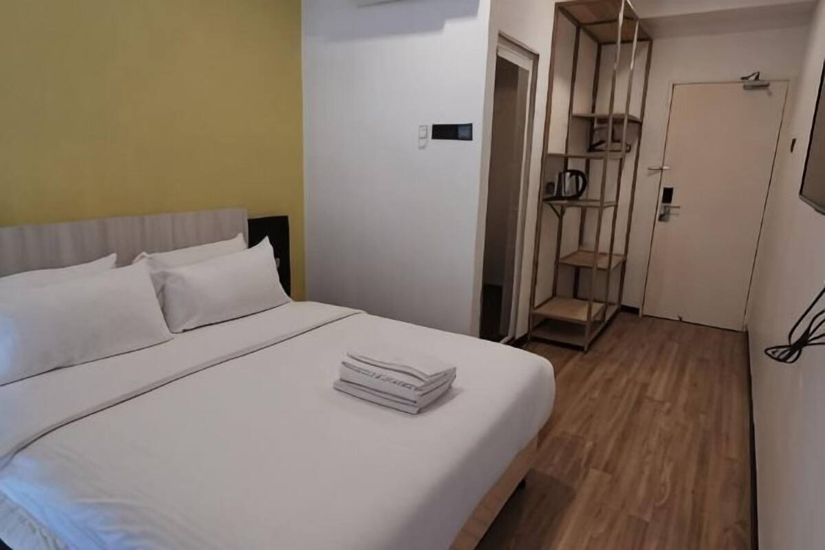 A hotel room with a bed, a wardrobe, and a door.