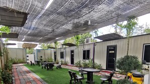 A covered outdoor area with artificial grass, picnic tables, and a pathway. - TT Dorf Hotel Matang (Taiping)