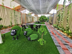 A patio area with artificial grass, a table and chairs, and decorative sheep figures.