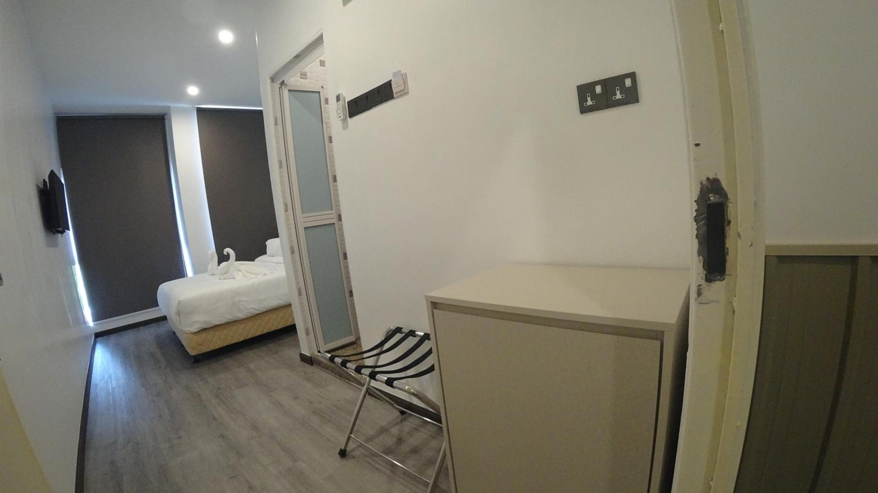 A hotel room with a bed, a small desk, a chair, and a wardrobe.