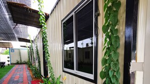 A pathway leading to a building with a window and a door, surrounded by greenery and plants. - TT Dorf Hotel Matang (Taiping)
