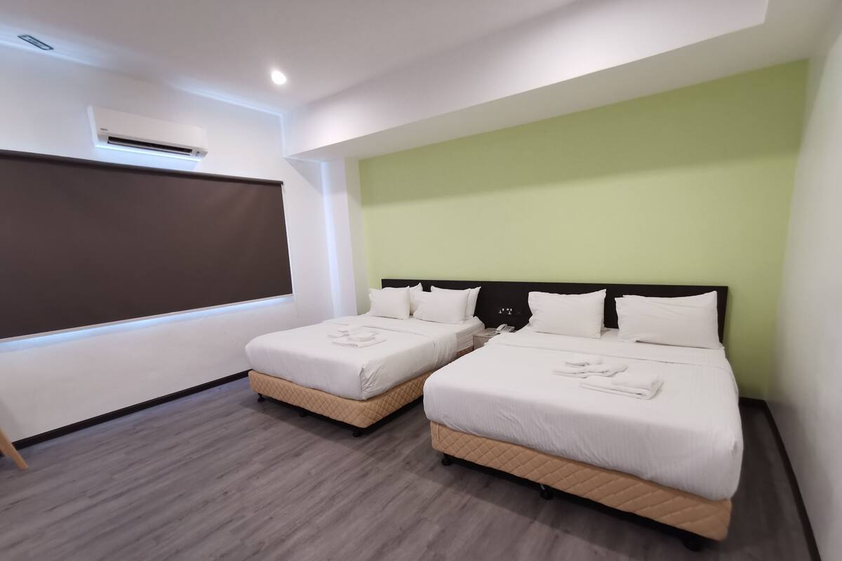 A hotel room with two beds, a large window, and a projector screen.