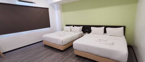 Habitación de hotel con dos camas, un ventanal grande y una pantalla de proyector.