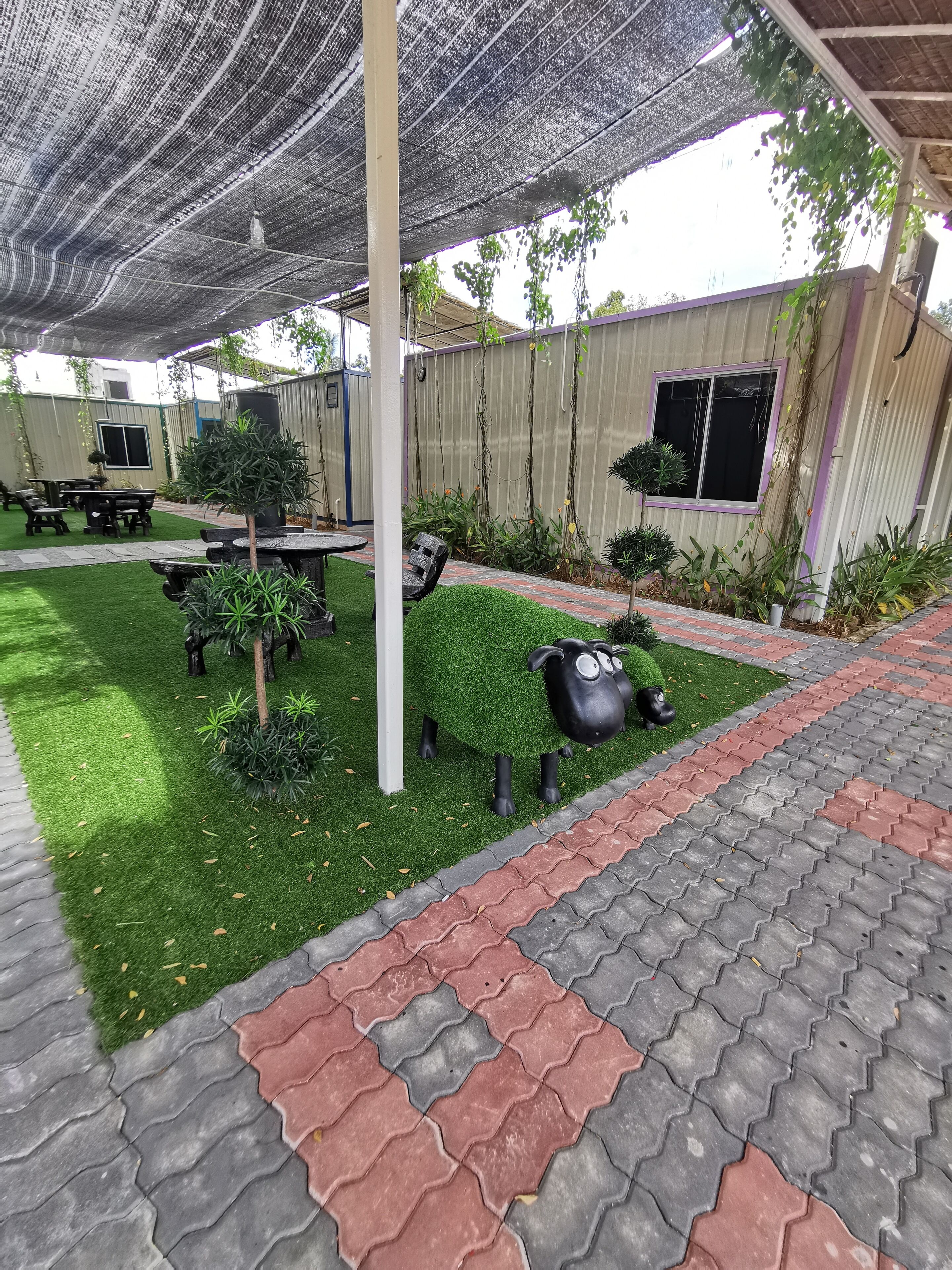 Un espacio al aire libre cubierto con patio, césped artificial y un conjunto de asientos.