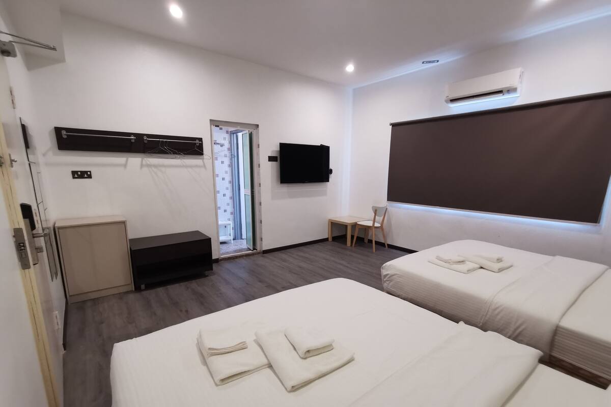 A hotel room with two beds, a TV, a desk, and a chair.