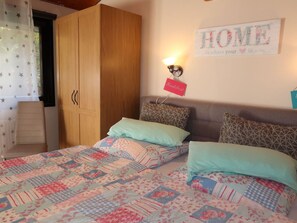 Relax in this inviting bedroom with a large bed, adorned with a colorful patchwork quilt and flanked by matching pillows.