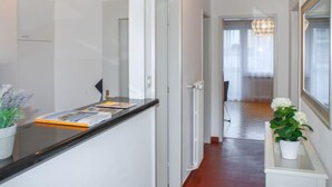 A hallway with a reception desk, a potted plant, and a chandelier. - Junior Suite by Interhome (Ascona)