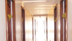 Un largo pasillo bien iluminado con puertas de madera y suelo de baldosas.