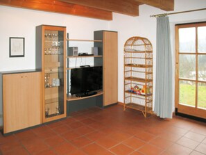 Cozy living space with a television, shelving units, and a wicker basket.