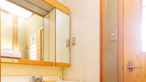 Une salle de bain avec un meuble-lavabo en bois, un évier, un miroir et une porte.