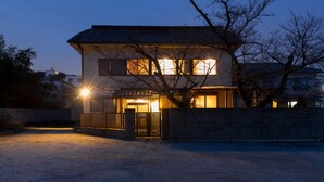 Une maison à deux étages avec une entrée bien visible à l’avant et une cour clôturée.