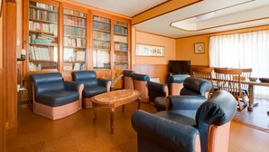 Une bibliothèque avec des canapés en cuir, une table basse en bois et des étagères remplies de livres.