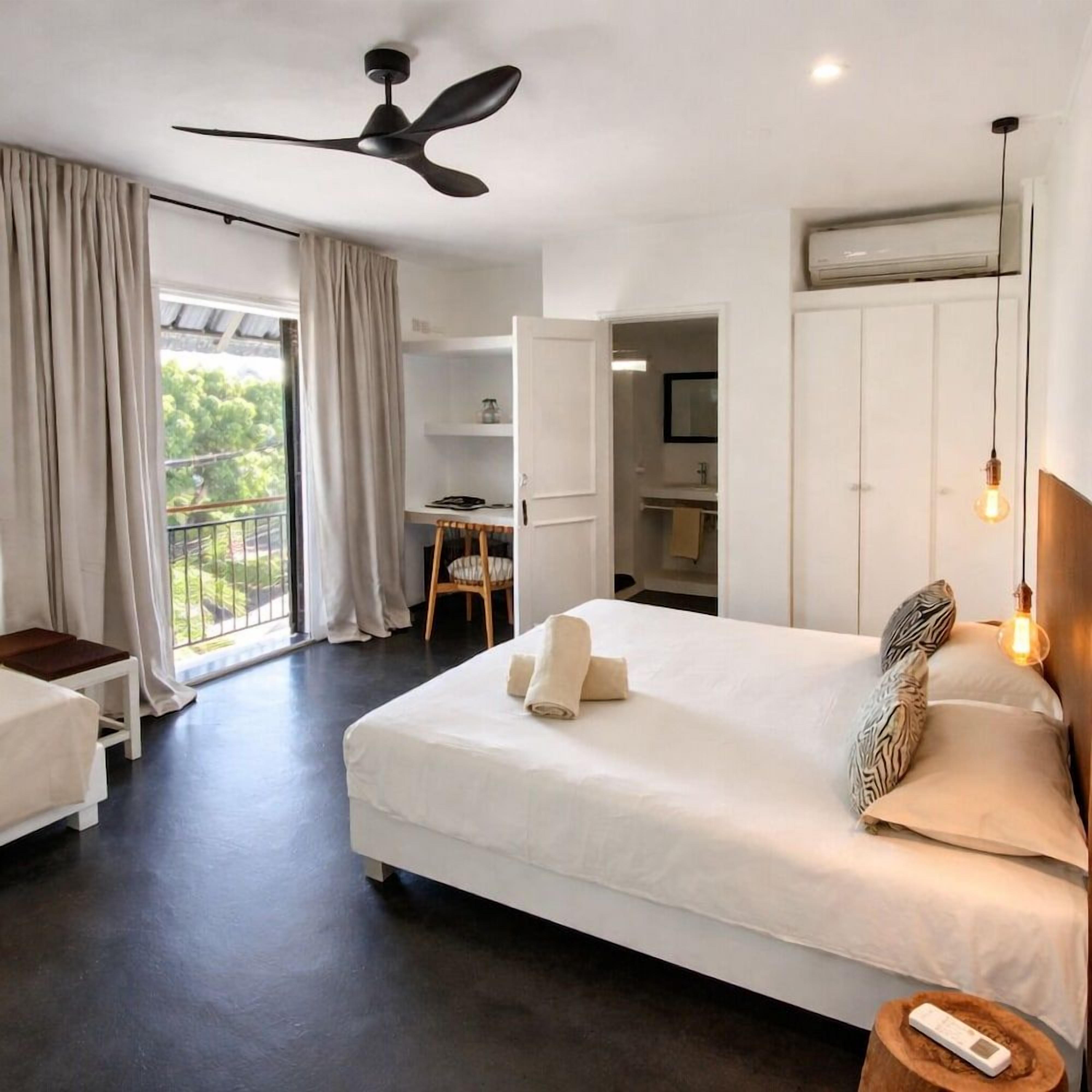 Una habitación de hotel con cama, escritorio, silla y balcón.