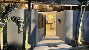 A gated entrance to a building with a reception desk visible inside. - Sous le Badamier (pointe aux canonniers)