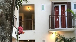A courtyard with a wooden table and chairs, potted plants, and a tree. - Sous le Badamier (pointe aux canonniers)