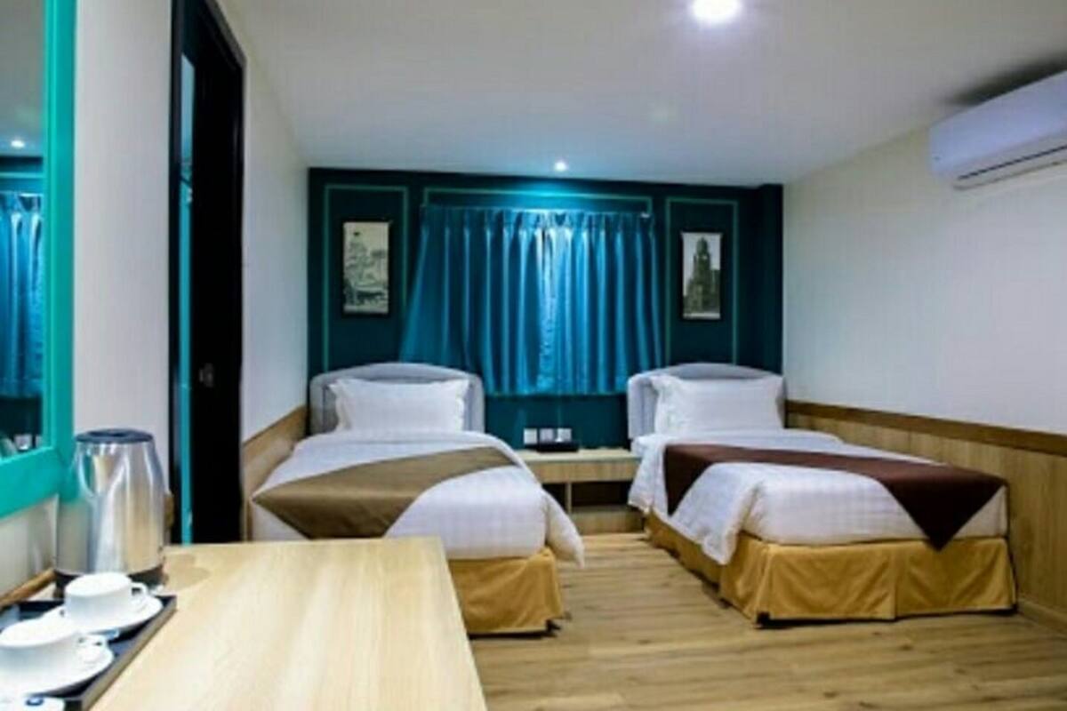 A hotel room with two single beds, a wooden table with a tray of breakfast items, and a window with curtains.