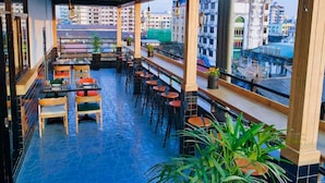 A rooftop restaurant with outdoor seating, potted plants, and a view of the cityscape. - Sanctuary Hotel Yangon (Yangon)