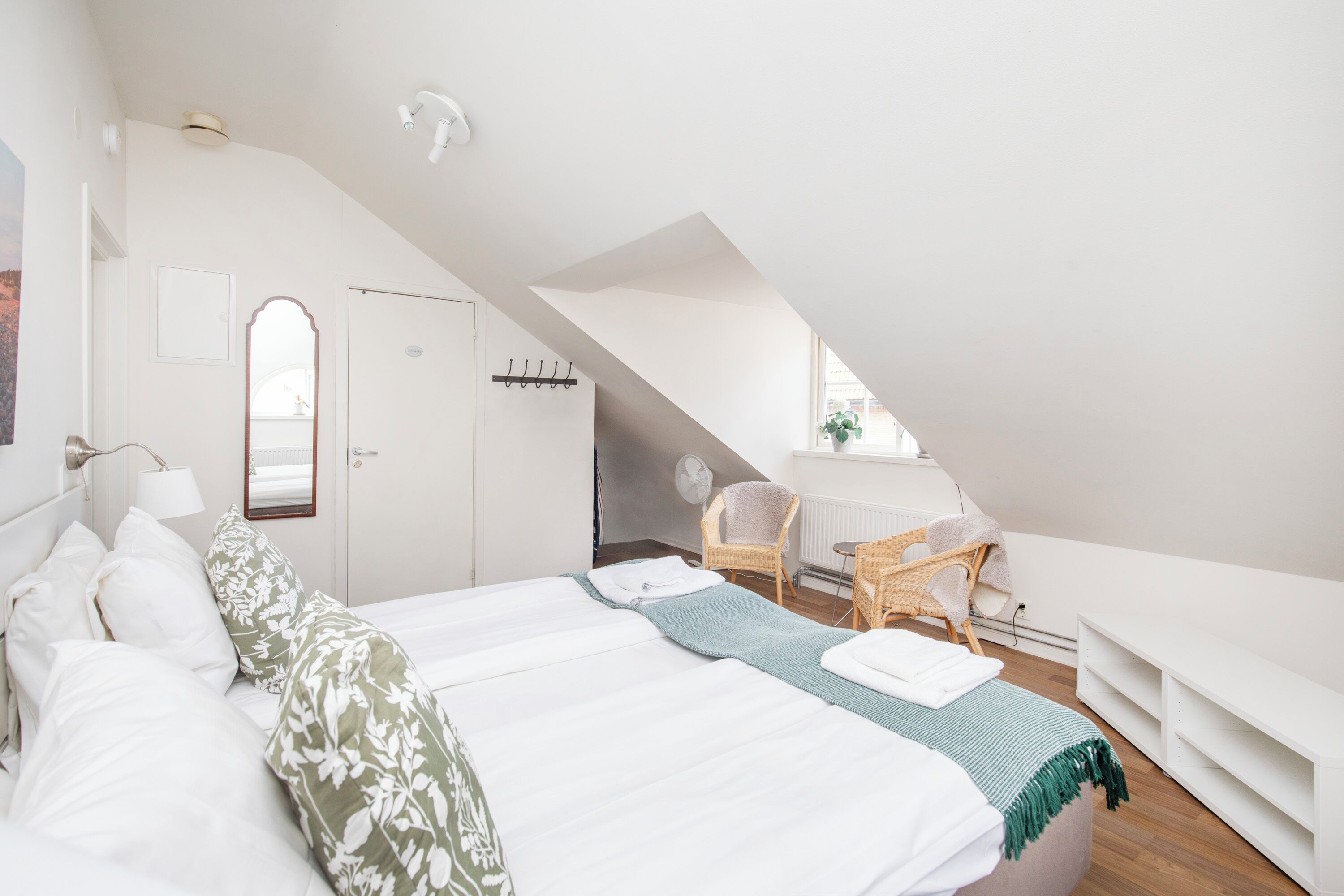 A bedroom with a large bed, a chair, a radiator, and a window.