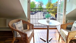 Un balcón con muebles de mimbre y vista a la calle.
