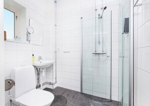 A modern bathroom with a glass-enclosed shower, a white sink, and a toilet.