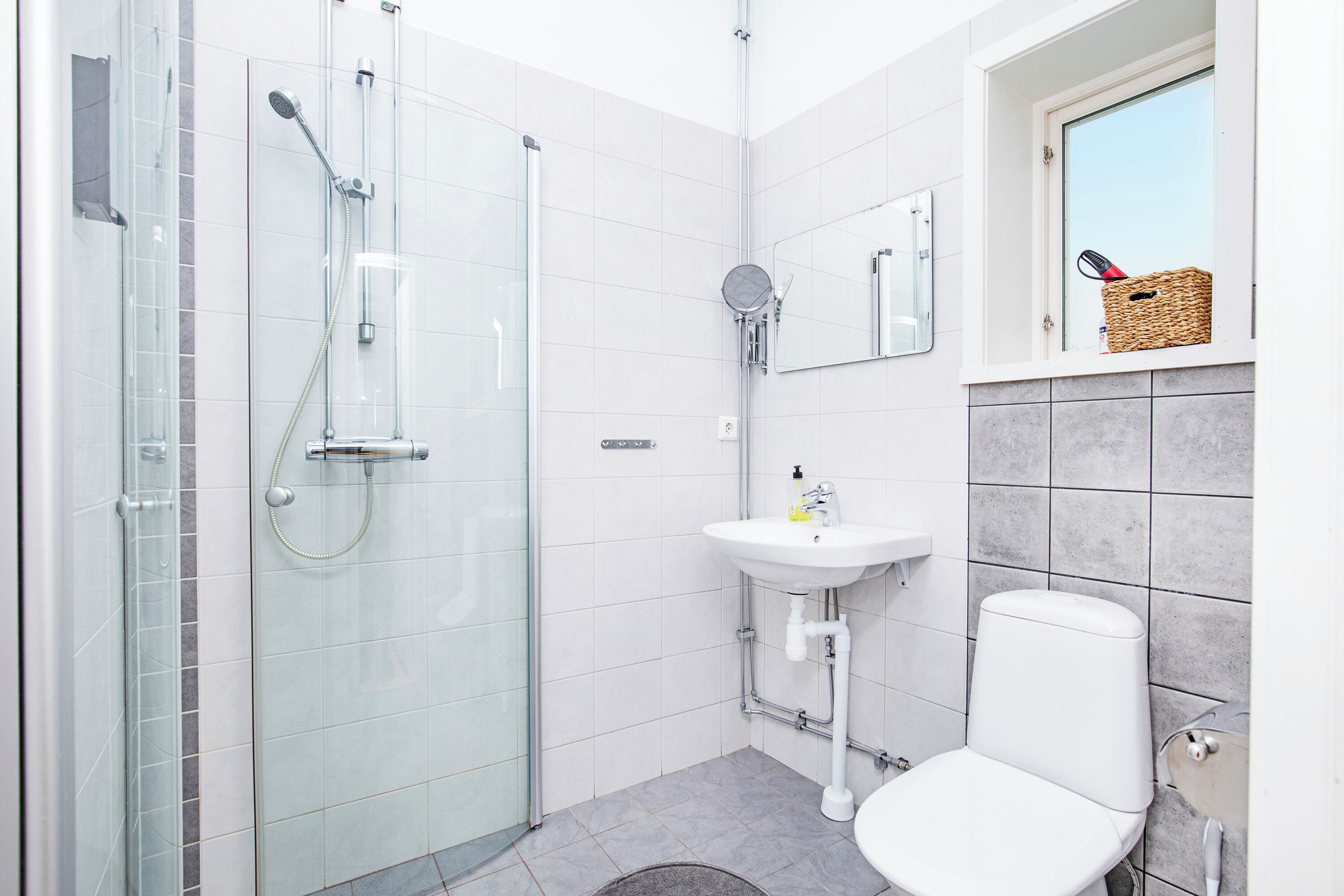 A modern bathroom with a glass shower enclosure, a white sink, and a toilet.