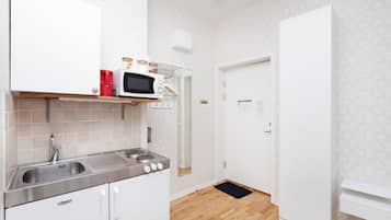 Een keuken met witte kastjes, een roestvrijstalen spoelbak, een magnetron en een rode koffiezetapparaat.