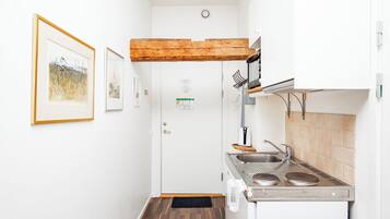A compact kitchen with a wooden beam ceiling, a sink, and a stove.