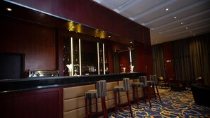 A bar area with a counter, bar stools, and a patterned carpet. - Daamat Hotel (Addis Ababa)